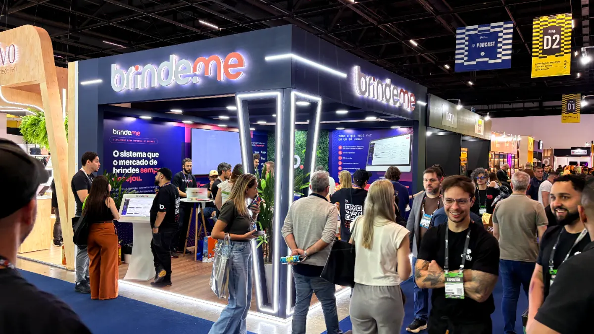 Estande da Brinde.me movimentado durante a feira, com visitantes conhecendo a plataforma nos totens